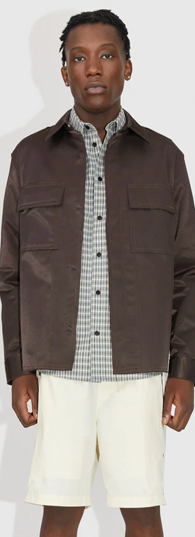 A man wearing a brown Wood Wood jacket with a checkered button up and beige shorts