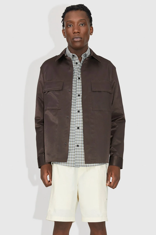 A man wearing a brown Wood Wood jacket with a checkered button up and beige shorts
