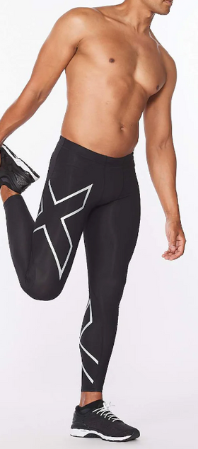 A man wearing no shirt and 2XU running pants while stretching
