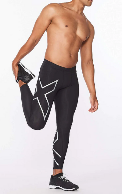 A man wearing no shirt and 2XU running pants while stretching