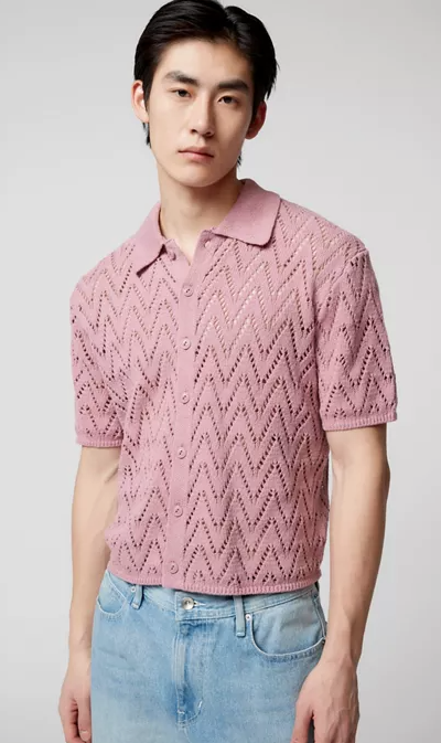 A man wearing a trendy Urban Outfitters pink collared shirt and denim pants