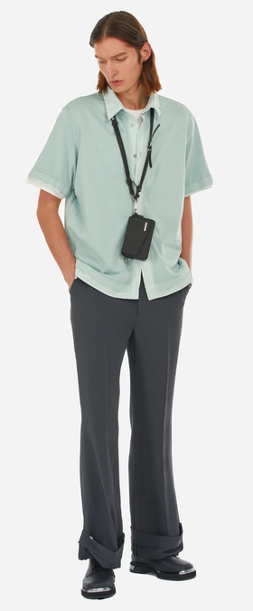 A man wearing a C2H4 button up shirt with black bell bottomed pants