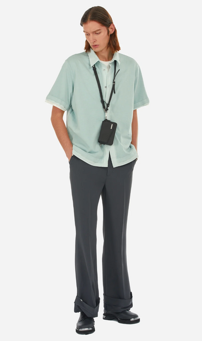 A man wearing a C2H4 button up shirt with black bell bottomed pants