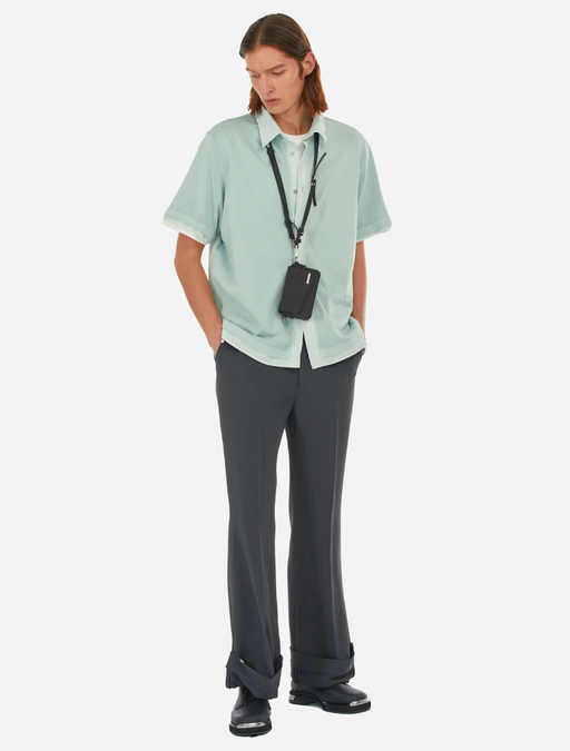 A man wearing a C2H4 button up shirt with black bell bottomed pants