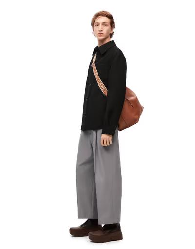A man wearing a Loewe sweater and grey wide pants