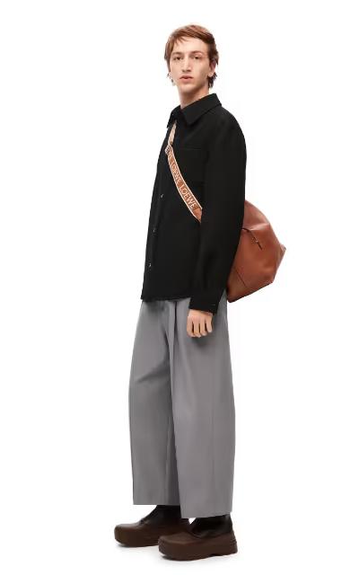 A man wearing a Loewe sweater and grey wide pants