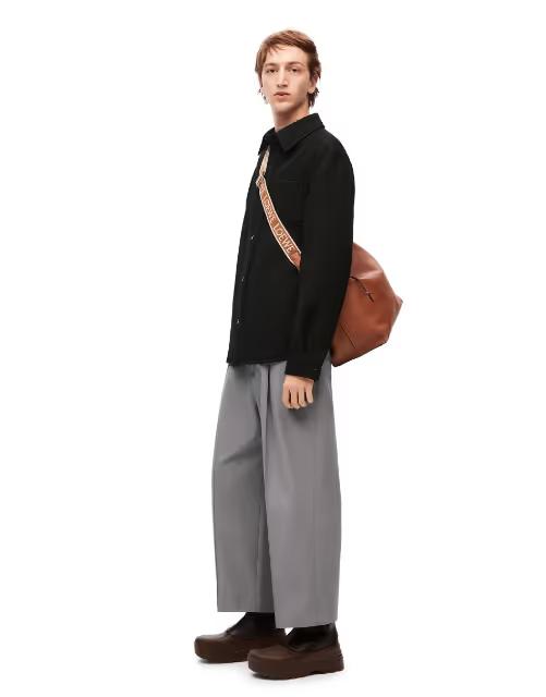A man wearing a Loewe sweater and grey wide pants