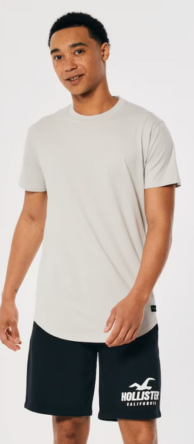 A man wearing a Hollister t-shirt and athletic branded shorts
