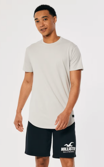 A man wearing a Hollister t-shirt and athletic branded shorts