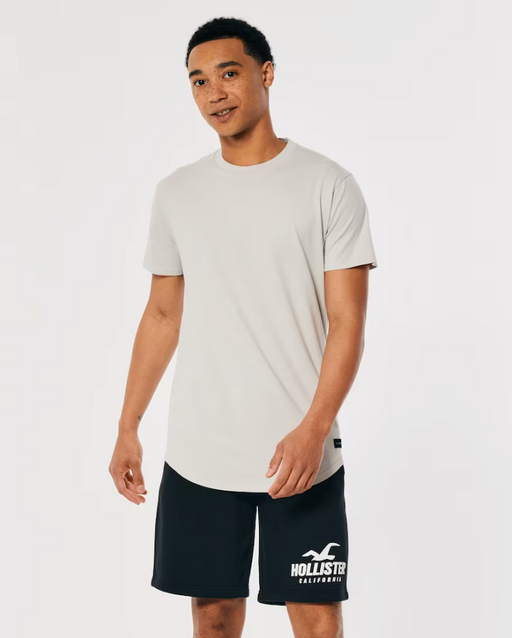 A man wearing a Hollister t-shirt and athletic branded shorts