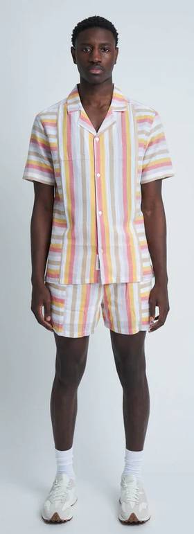 A man wearing a pinstripe Native Youth button up with matching shorts