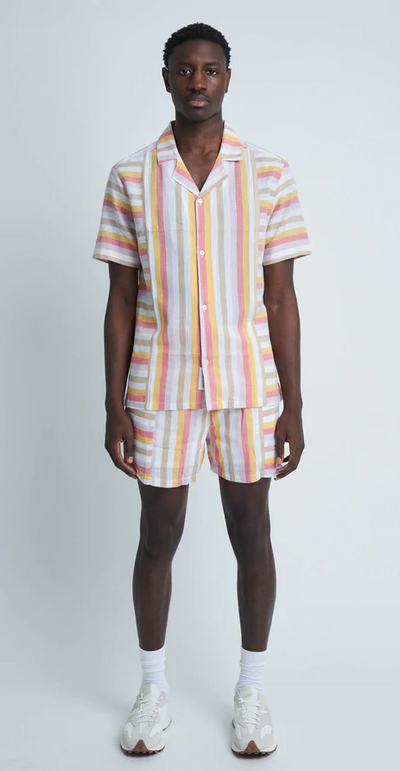 A man wearing a pinstripe Native Youth button up with matching shorts