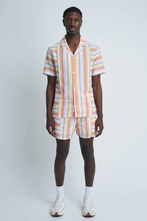 A man wearing a pinstripe Native Youth button up with matching shorts