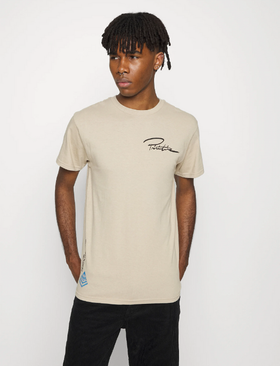 A man wearing a branded logo Primitive beige t-shirt and black pants