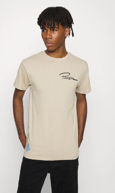 A man wearing a branded logo Primitive beige t-shirt and black pants