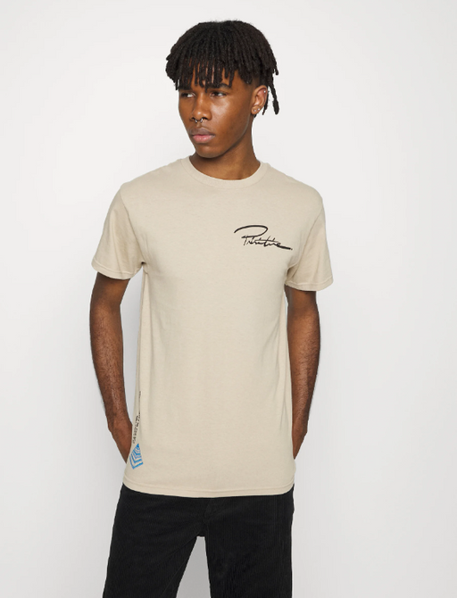 A man wearing a branded logo Primitive beige t-shirt and black pants