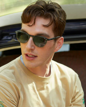 A man wearing a pair of krewe sunglasses while wearing a yellow shirt