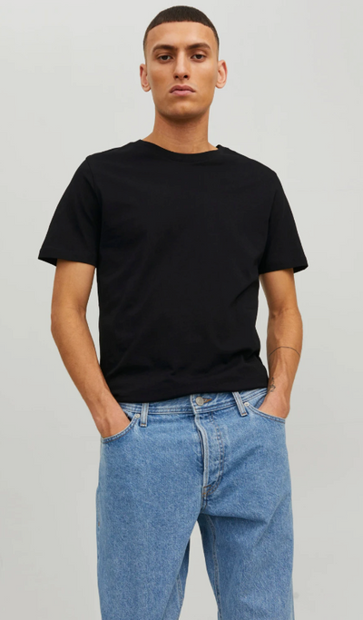 A man wearing a black Jack & Jones t-shirt with blue washed jeans
