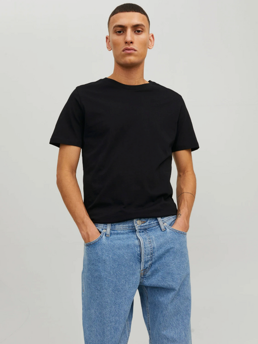 A man wearing a black Jack & Jones t-shirt with blue washed jeans