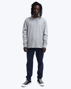 A man wearing a grey Reigning Champ long-sleeve with black pants and Converse shoes