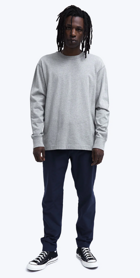 A man wearing a grey Reigning Champ long-sleeve with black pants and Converse shoes