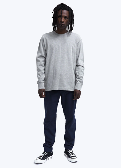 A man wearing a grey Reigning Champ long-sleeve with black pants and Converse shoes