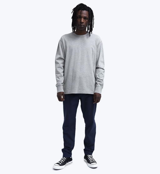 A man wearing a grey Reigning Champ long-sleeve with black pants and Converse shoes