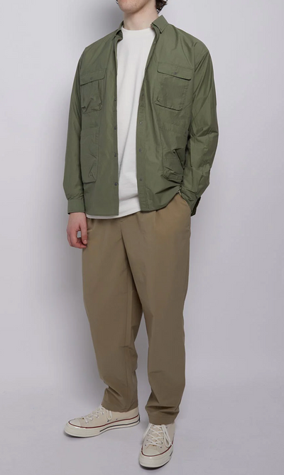 A man wearing a Nigel Cabourn outfit featuring a green light jacket and brownish green pants