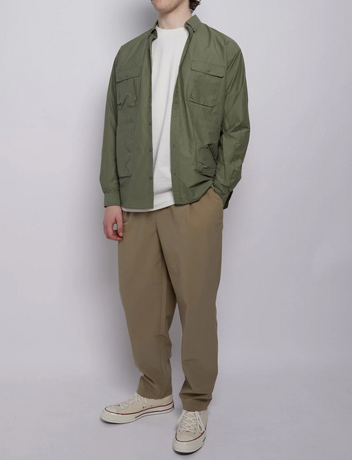 A man wearing a Nigel Cabourn outfit featuring a green light jacket and brownish green pants
