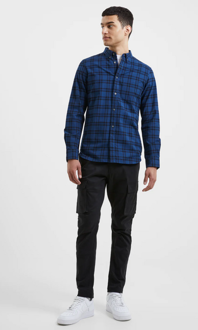 A man wearing a checkered plaid French Connection blue button up with black pants