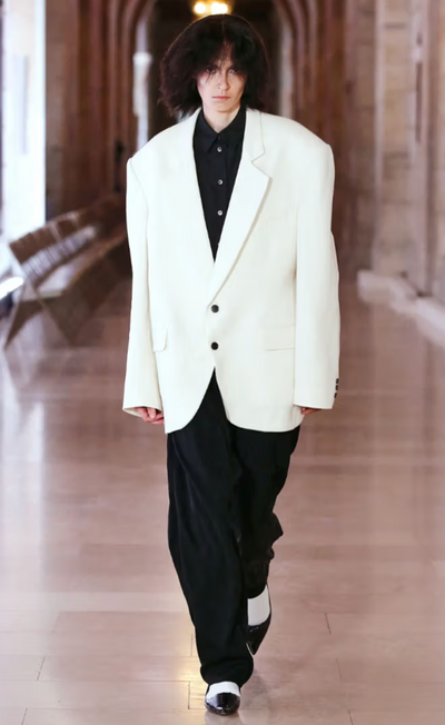 A man wearing a designer Marc Jacobs white suit jacket and black pants