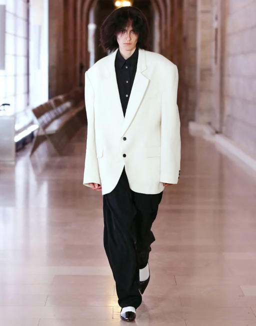 A man wearing a designer Marc Jacobs white suit jacket and black pants