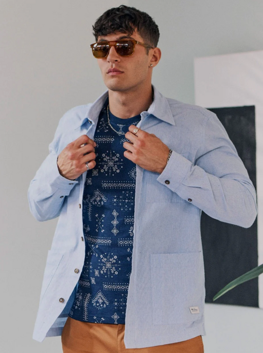 A man wearing a blue Ben Sherman button up shirt and blue t-shirt underneath