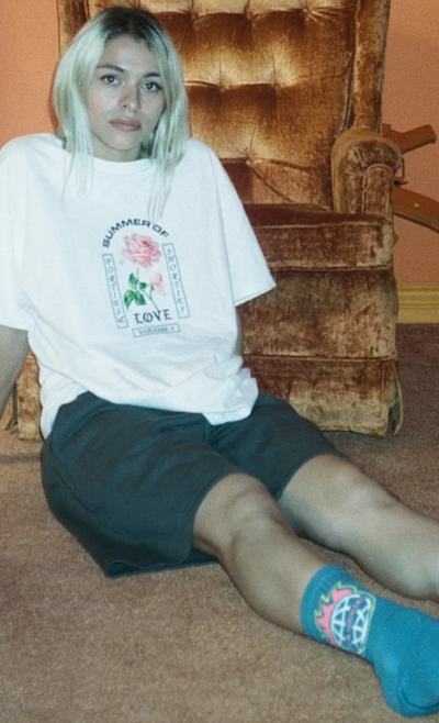 A woman wearing a 40s and Shorties white t-shirt and shorts