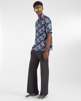 A man wearing a designer Fendi logo t-shirt and black bell-bottomed pants