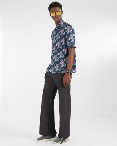 A man wearing a designer Fendi logo t-shirt and black bell-bottomed pants