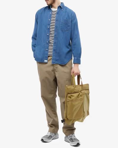 A man wearing orSlow denim shirt and khaki pants