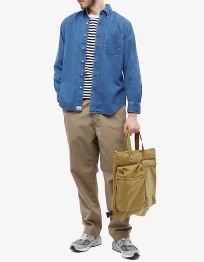 A man wearing orSlow denim shirt and khaki pants