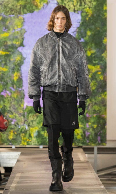 A man walking a runway wearing a 1017 ALYX 9SM outfit with a jacket and black pants