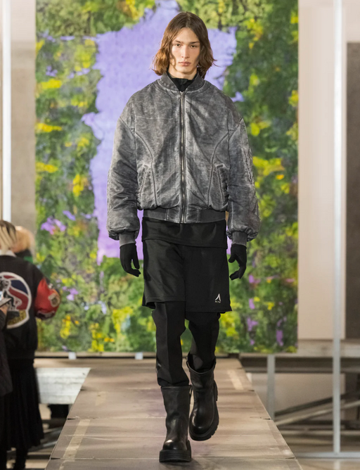 A man walking a runway wearing a 1017 ALYX 9SM outfit with a jacket and black pants