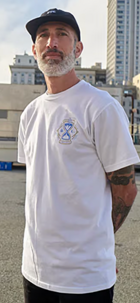 A man standing wearing a Benny Gold white t-shirt and black hat