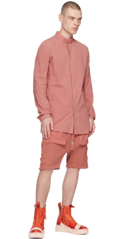 A man wearing a Boris Bidjan Saberi light red button up, shorts and bright red boots