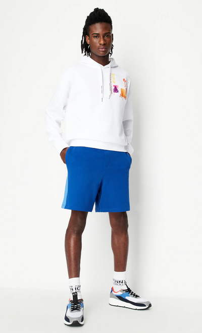 A man wearing a white Armani Exchange hoodie and blue shorts