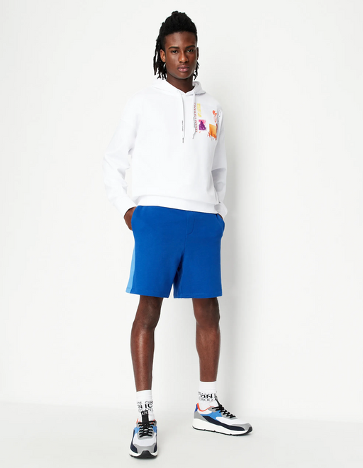 A man wearing a white Armani Exchange hoodie and blue shorts