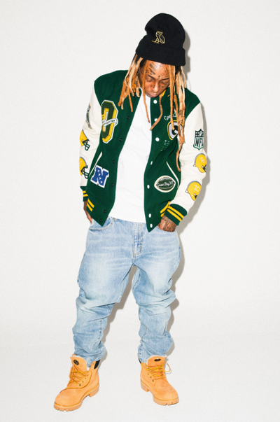 Lil Wayne wearing an OVO varsity jacket, jeans and Timberlands