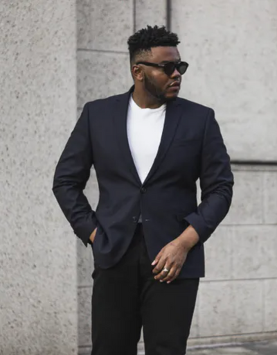 A man wearing a black Kenneth Cole suit with sunglasses