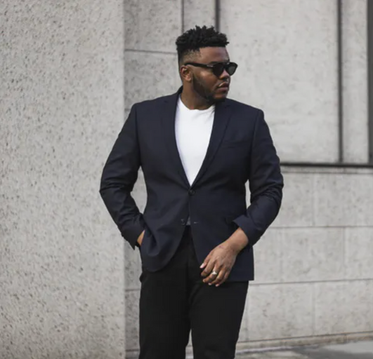 A man wearing a black Kenneth Cole suit with sunglasses