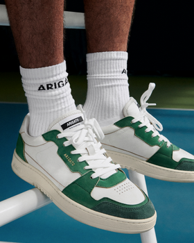 A man wearing Axel Arigato green and white shoes and white branded socks