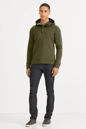 A man wearing a Nau olive green sweater and jeans