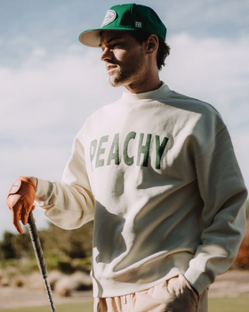 A man wearing a Devereux Golf grey 'Peachy' sweater and green hat